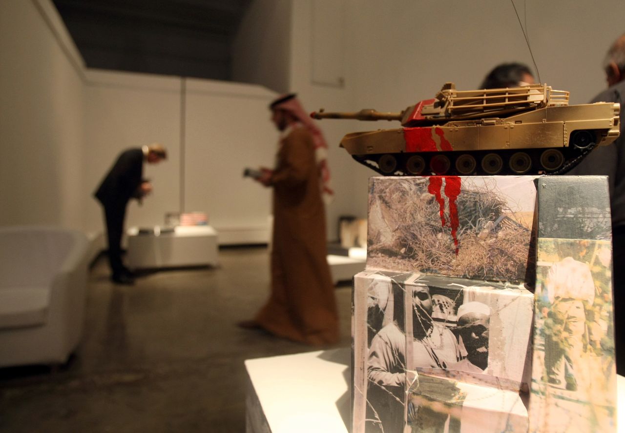 Visitors look at an artwork entitled "The Ugly Face of Occupation 2009" by Iraqi artist Dia Azzawi displayed at "My Home Land" exhibition in Dubai in 2010. Seven Iraqi artists living outside Iraq took part in the exhibition. 