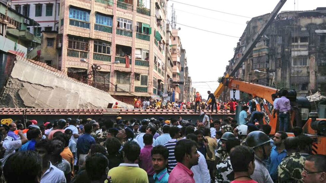 People watch as residents and rescue workers clear the debris on March 31.