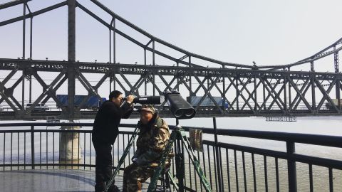 A Chinese tourist peeks into North Korea through a pair of binoculars at the border in Dandong, China. A look costs 5 yuan or 80 U.S. cents.