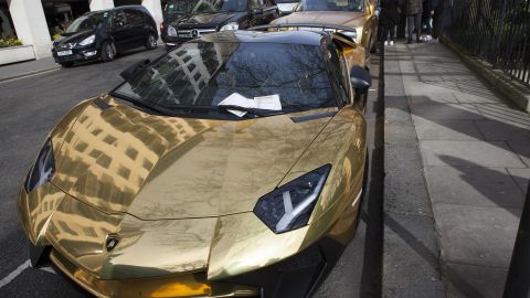 A luxury gold car parked in London is hit with parking fines.