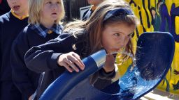 Schoolchildren queue to drink from a new public drinking fountain.  AFP PHOTO/Penny SPANKIE