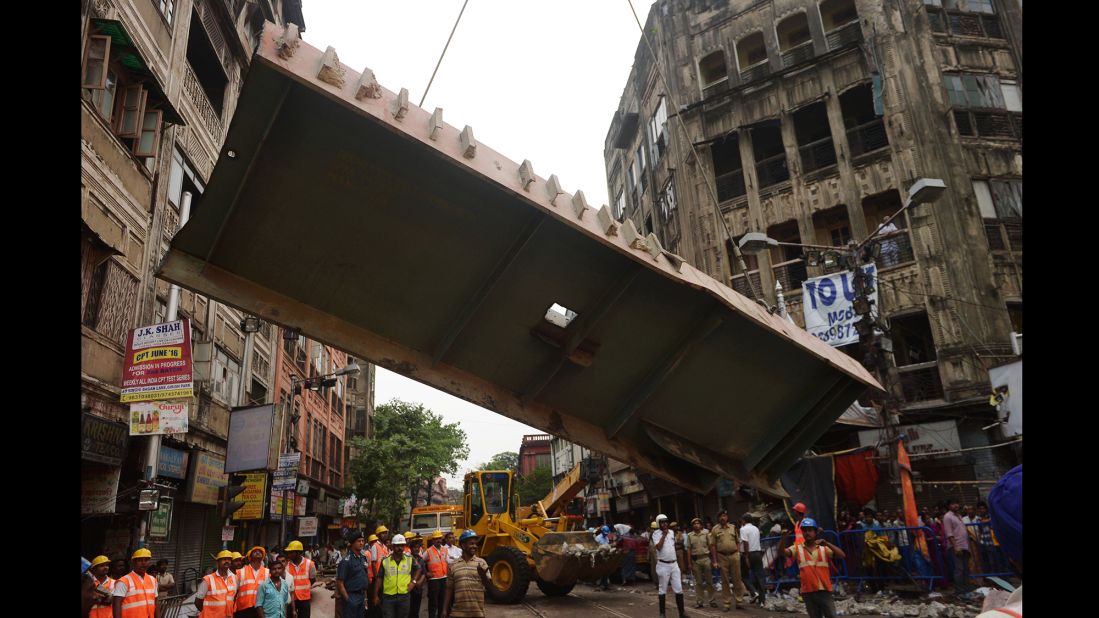 Workers remove a section of the collapsed overpass on Friday, April 1.