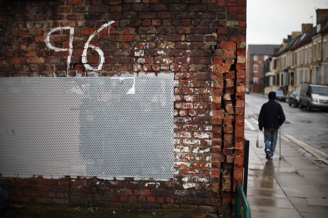 A man walks past "Justice for the 96" graffiti near Anfield soon after the High Court quashed verdicts of accidental death on December 19, 2012. New inquests into the disaster were ordered.