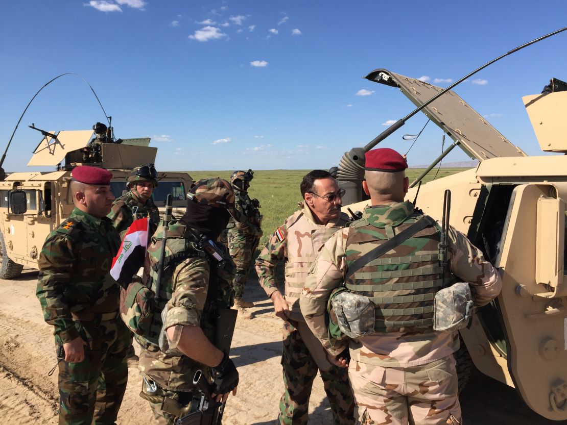 Major General Najim al-Jobori (wearing sun glasses) puts on body armor as his team heads for the front line.