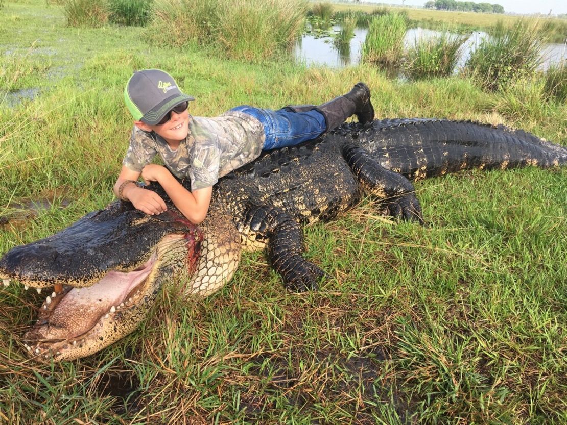 Mason Lightsey on top of the alligator that was hunted at Outwest Farms in Florida.