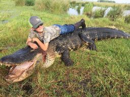 Mason Lightsey on top of the alligator that was hunted at Outwest Farms in Florida.