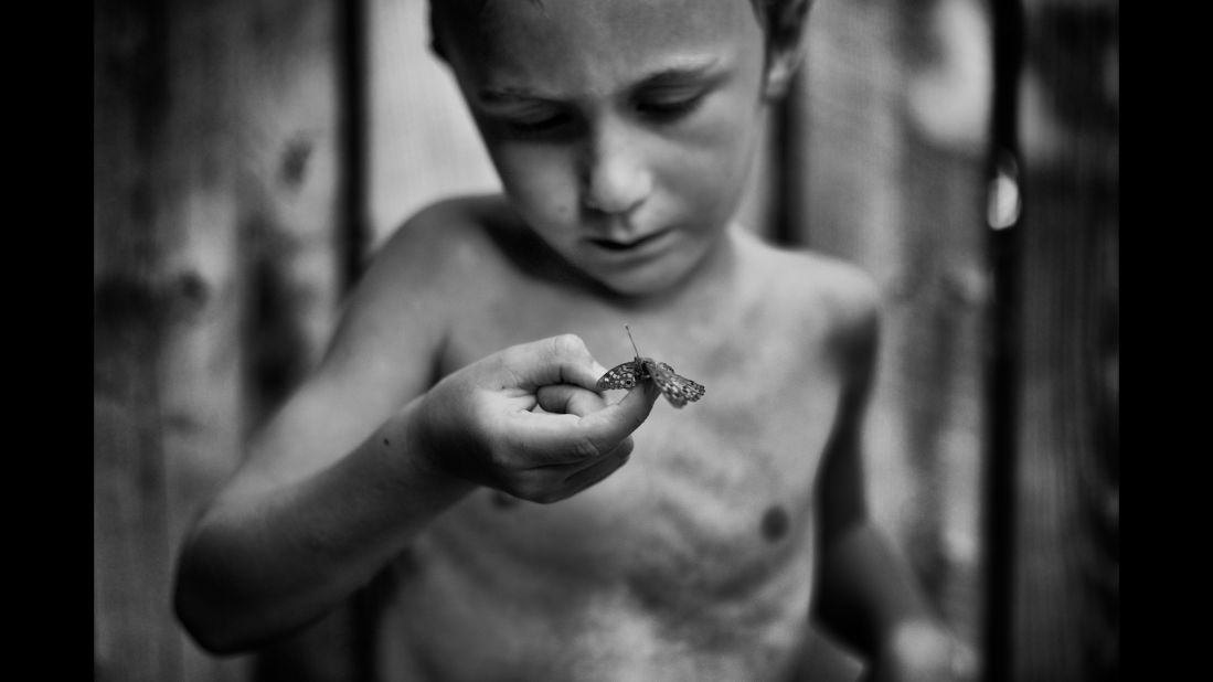 Tharin, the son of photographer Tytia Habing, inspects a moth they found by the pool. Habing has been photographing Tharin as he explores their farm in rural Illinois. "I hope people will look at (the photos) and remember that kids need to be outside," she said.