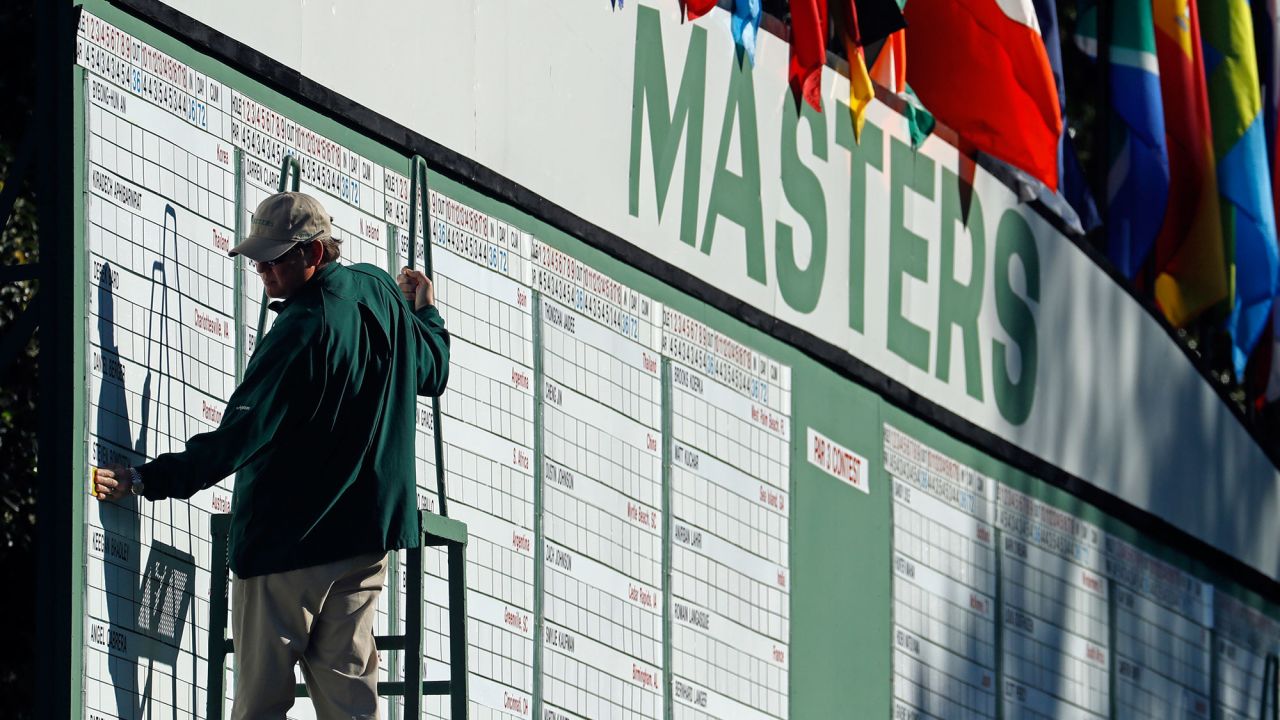 A scorekeeper places numbers on the leaderboard during the first round.