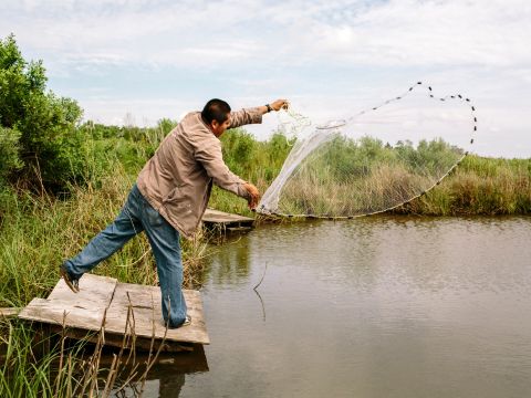 George Hernandez throws a cast net at the entrance to Isle de Jean Charles. Hernandez is a resident of nearby Houma, Louisiana, and he often travels to the island to fish. It's about 1.5 hours by car south of New Orleans.