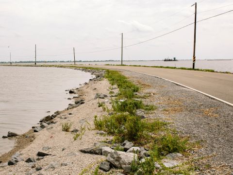 When tides are high and winds are blowing, Island Road sometimes becomes impassable. Isle de Jean Charles is vulnerable to hurricanes and flooding. The marsh is disappearing and seas are rising because of global warming.