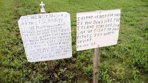 Not everyone wants to leave the island. "Some people want to move. They can go," says a handwritten sign posted beside Island Road. "But leave us alone."