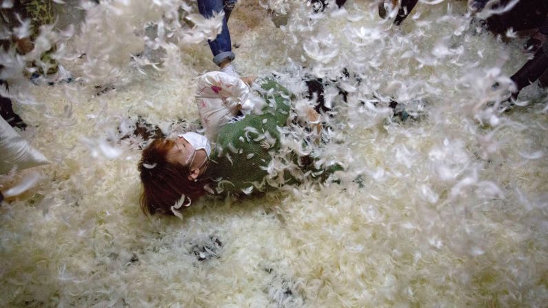 A pillow-fight participant falls to a floor covered with feathers Saturday, April 2, in Beijing. It was<a href="http://pillowfightday.com" target="_blank" target="_blank"> International Pillow Fight Day,</a> and similar events were held across the world.