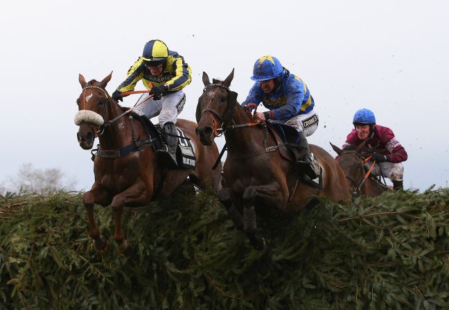 The Last Samuri (R) ridden by David Bass and Vics Canvas (L) ridden by Robert Dunne clear the last fence. However, in the background, eventual winner Rule The World and Mullins are planning their final move.