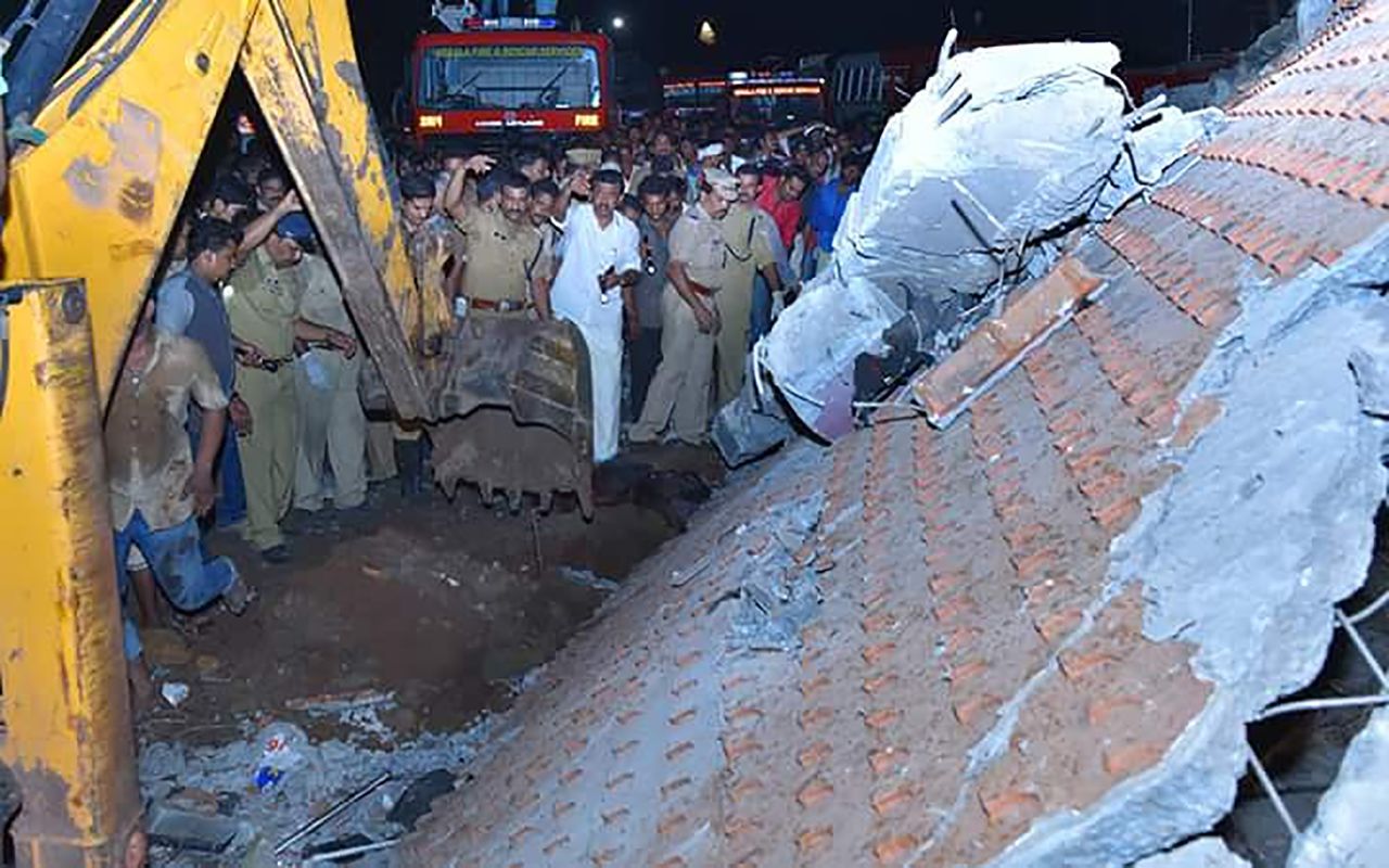 Indian officials and bystanders gather beside a collapsed building after the fire.