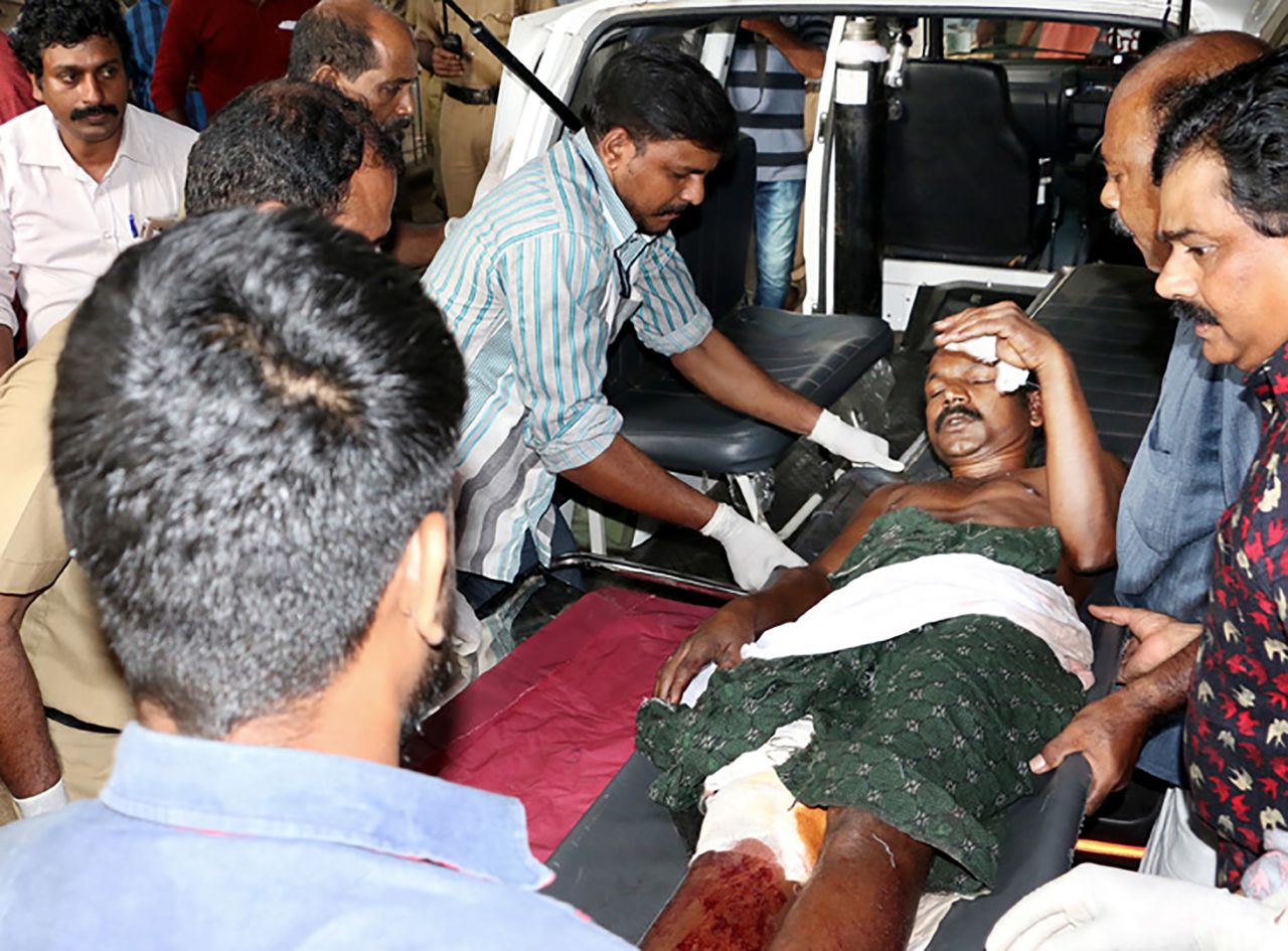 Indian medical officials and bystanders carry an injured man from a vehicle into a hospital in Paravur, India.