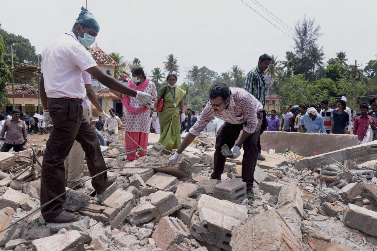 People search through the debris of a a collapsed building after a massive fire broke out during a fireworks display at the Puttingal temple complex in southern India on Sunday, April 10.  Scores of people were killed and hundreds more injured in the fire, caused when an unauthorized fireworks show ignited a separate batch of fireworks that were being stored at the temple complex.