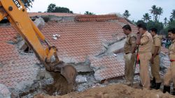 Indian officials look on as an excavator moves debris from a collapsed building after an explosion and fire at The Puttingal Devi Temple in Paravur early April 10, 2016.A massive fire swept through a temple in southern India, killing more than 100 people after thousands gathered to watch an illegal fireworks display. More than 280 others were injured in the fire that engulfed the Hindu temple complex in Kerala state, where crowds had built up during the night for a festival that boasted the fireworks show. / AFP / STR        (Photo credit should read STR/AFP/Getty Images)