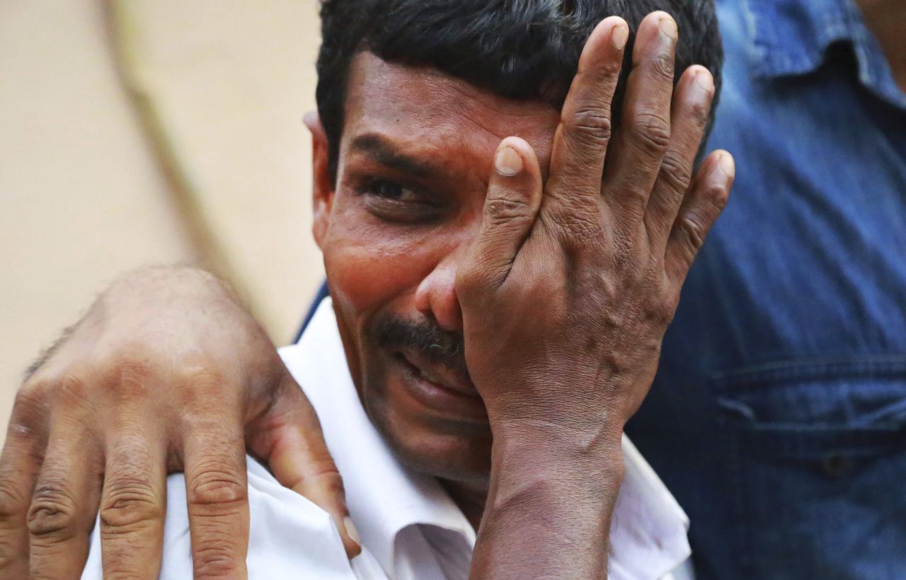 An unidentified man weeps as bodies of victims lie outside a morgue at the Kollam district hospital.