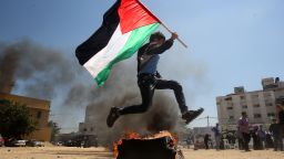 A Palestinian boy runs holding his national flag near a burning tyre as he acts out a scene for spectators visiting a building which used to be an Israeli prison where Palestinians were detained during Israel's occupation of Gaza on April 14, 2013. Hamas is organising tours of the facility which has been turned into a memorial centre. AFP PHOTO / MAHMUD HAMS        (Photo credit should read MAHMUD HAMS/AFP/Getty Images)