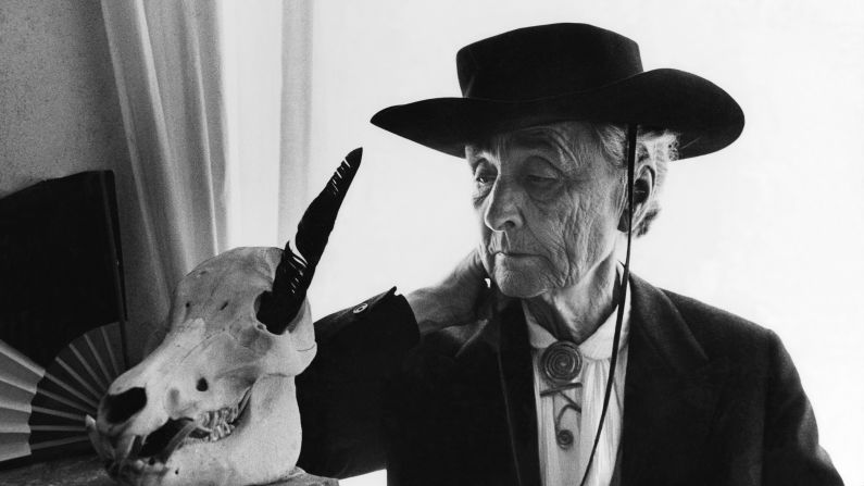 In 1967, artist Georgia O'Keeffe examines an animal skull with a black feather in one of its eye sockets.