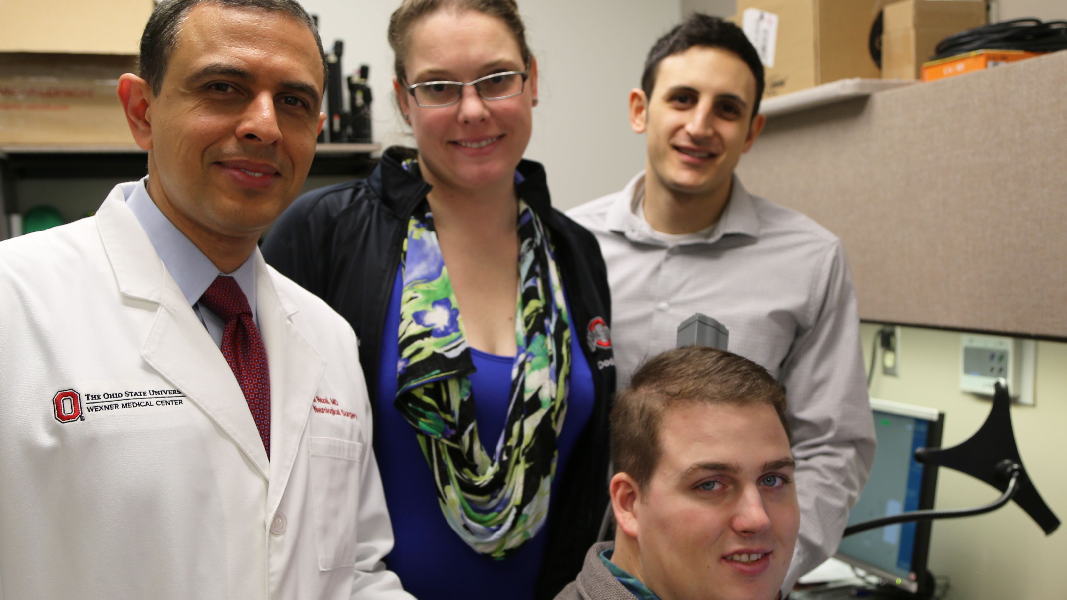 Patient Ian Burkhart, seated, poses with members of his research team during a neural bypass training session.
