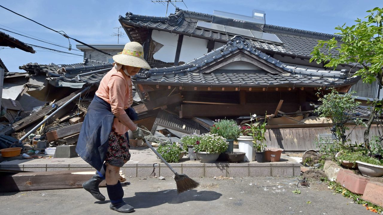 A woman cleans up in front of her collapsed house in Mashiki on April 15.  