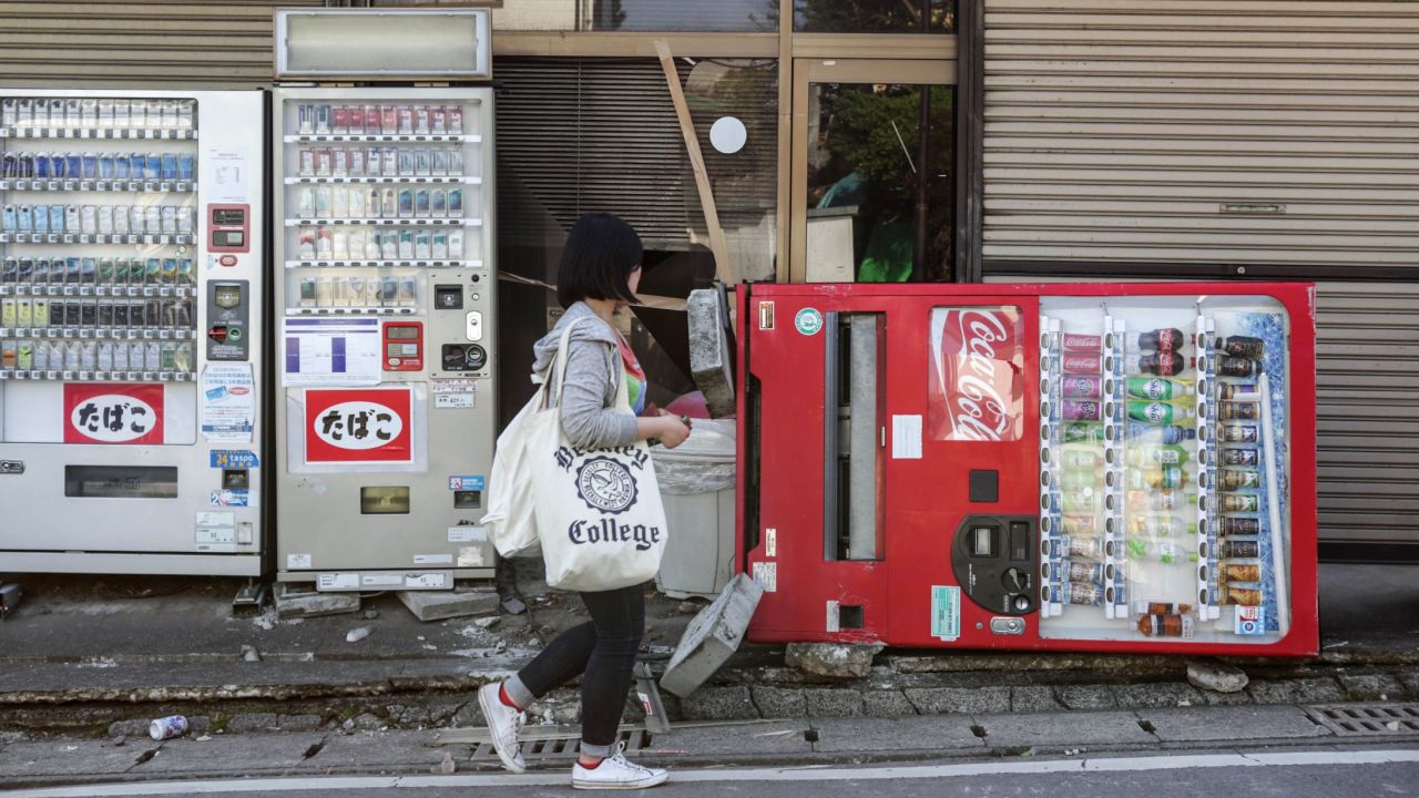 A resident passes by a toppled vending machine in Kumamoto on April 15.
