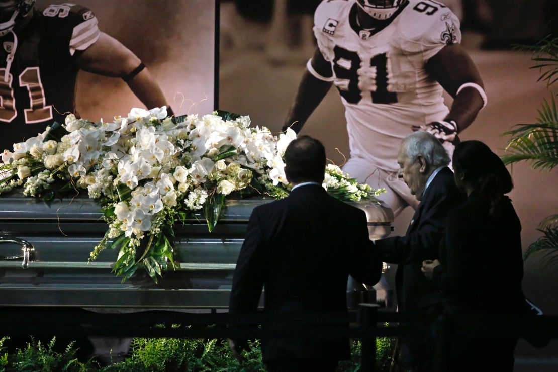 New Orleans Saints owner Tom Benson, right, stands in front of Will Smith's casket.