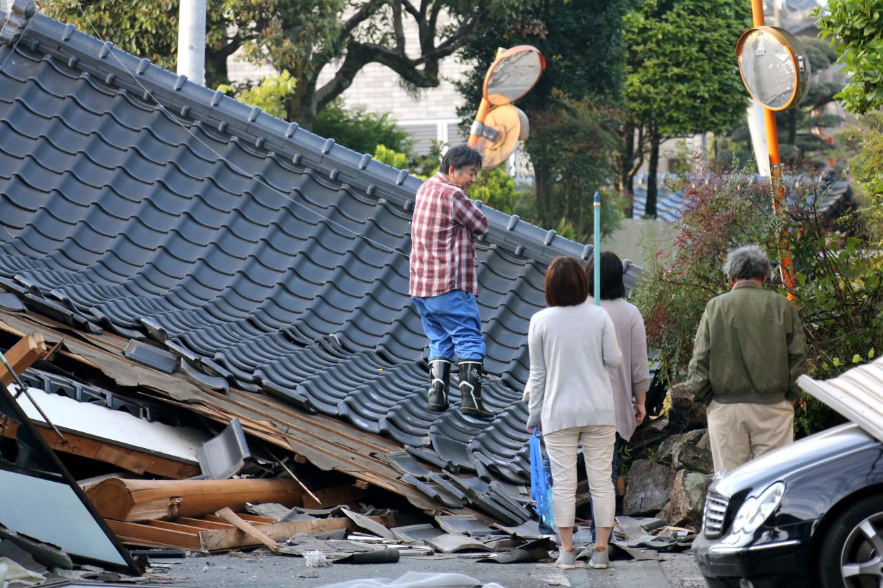 Residents look for an access to their homes on a road blocked by a collapsed house in Mashiki on April 16.
