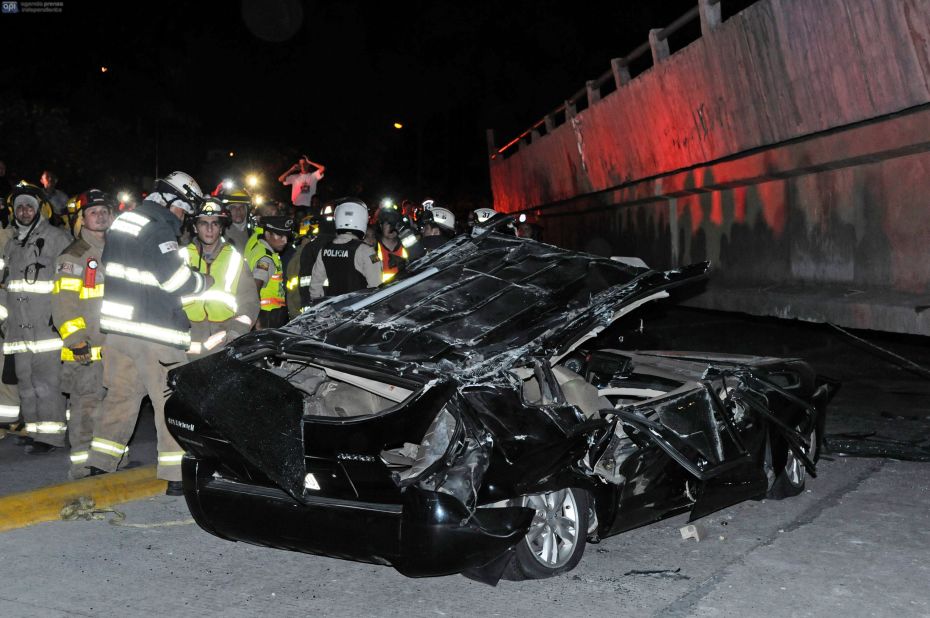 Rescue workers stand near a destroyed car in Guayaquil. 