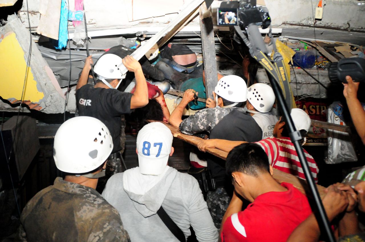 Rescue workers try to pull out survivors trapped in a collapsed building in Manta on April 17.