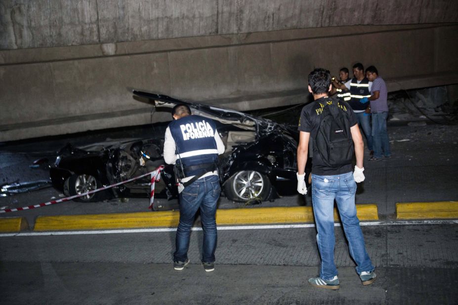 Police check out a car crushed under a collapsed overpass in Guayaquil. 