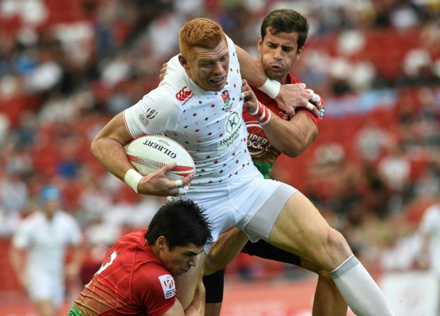 England's James Rodwell (C) struggles through Portugal players during their match at the Singapore Rugby Sevens tournament on April 16, 2016. 