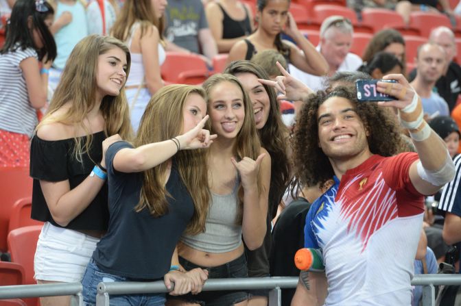 France's Pierre Gilles Lakafia (R) takes a selfie with fans during the Singapore Sevens rugby tournament on April 17, 2016. 