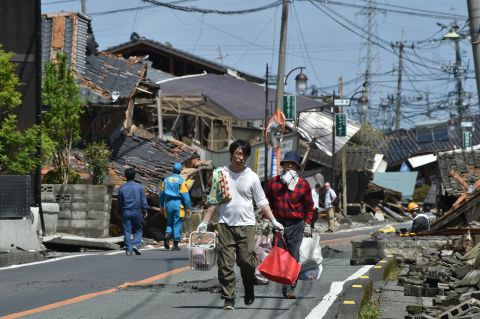 Residents walk down a street on April 17 surrounded by destroyed homes in Mashiki, Japan.