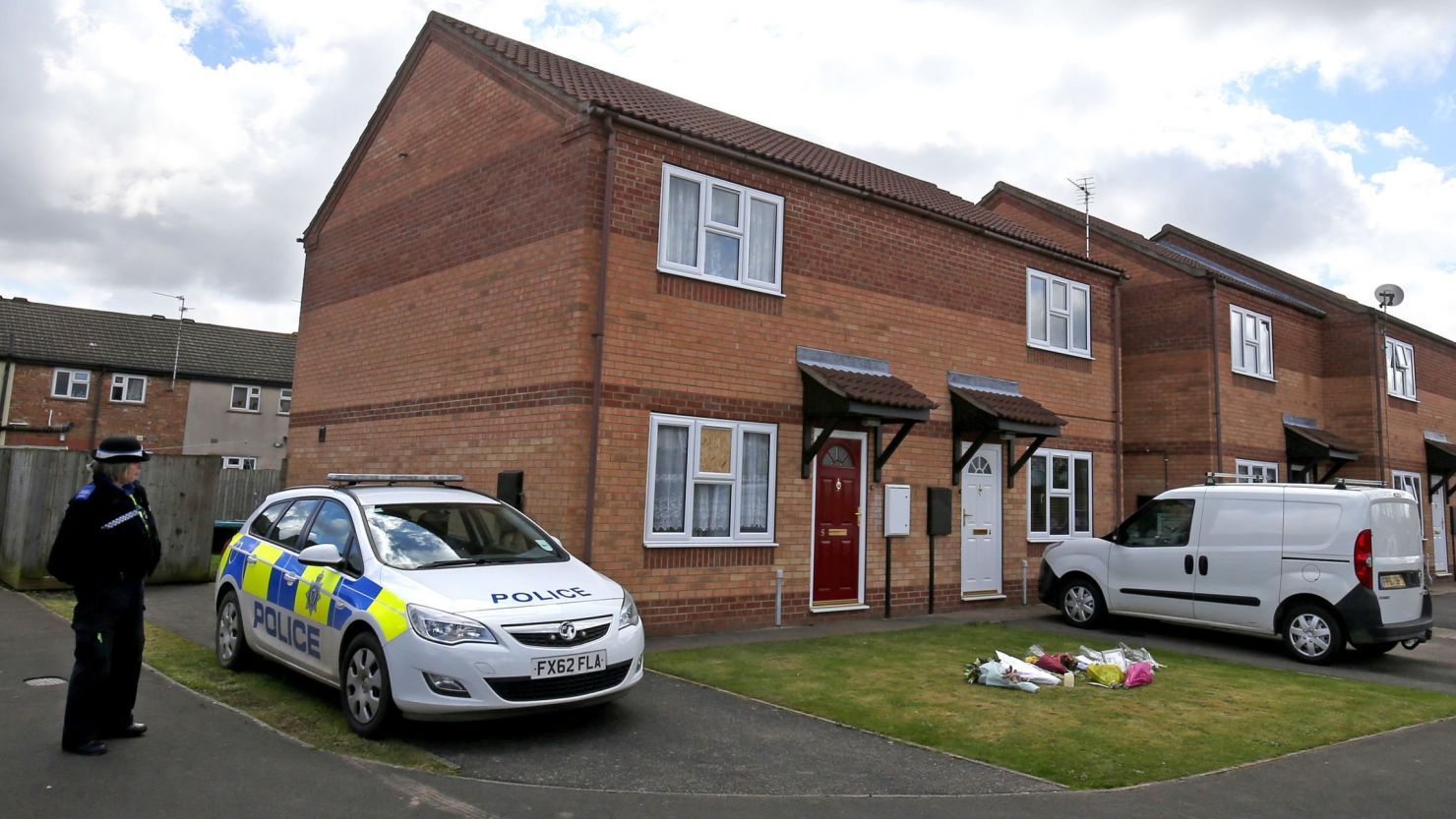 A police officer stands outside the home where a woman and her daughter were found dead. 