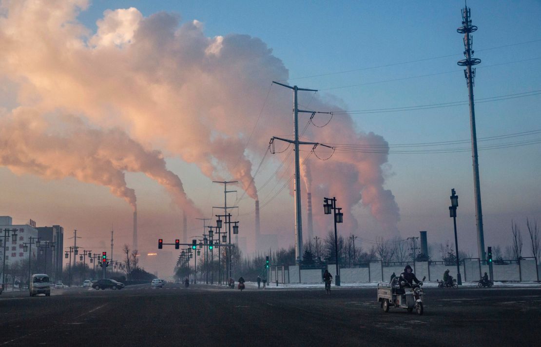 Chinese workers commute as smoke billows from a coal fired power plant on November 25, 2015 in Shanxi, China.