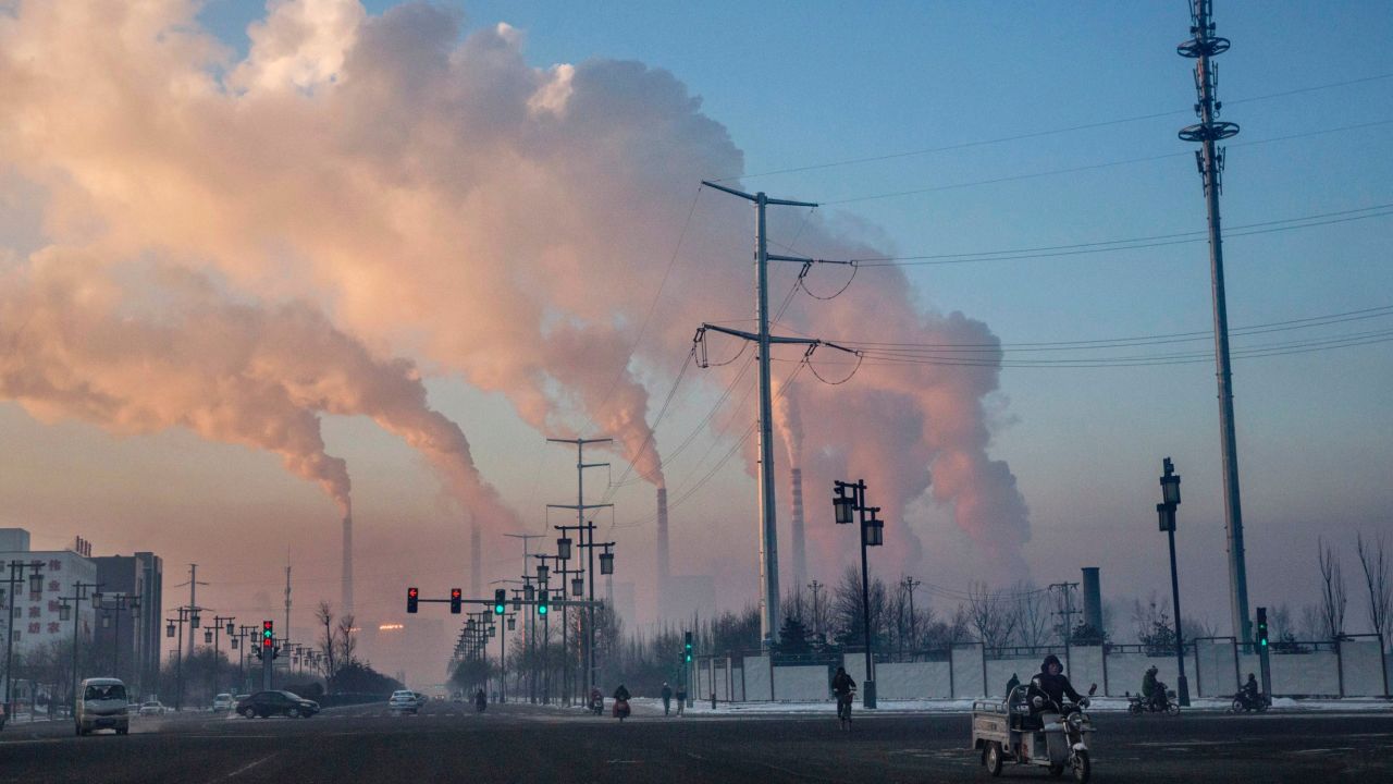 Chinese workers commute as smoke billows from a coal fired power plant on November 25, 2015 in Shanxi, China.