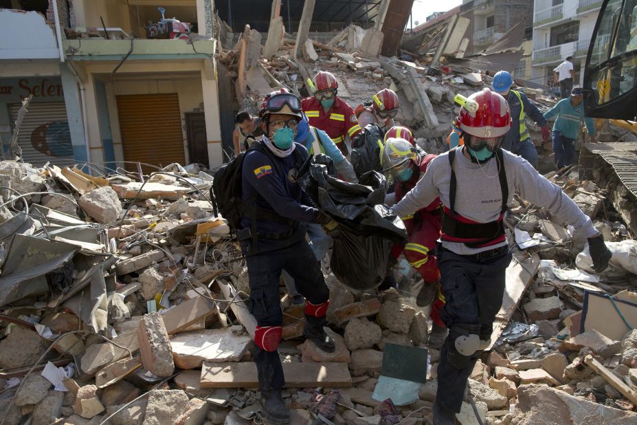 Firefighters remove a body from a destroyed building in Portoviejo on Monday, April 18.