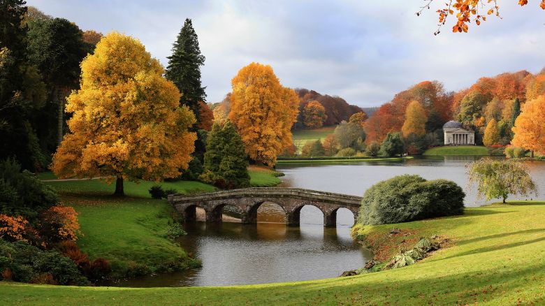 WARMINSTER, ENGLAND - NOVEMBER 03:  The sun shines on trees that are displaying their autumn colours surrounding Palladian bridge and the lakeside Pantheon at the National Trust's Stourhead on November 3, 2010 near Warminster, England. The UK is currently enjoying one of the best autumn displays for years, due in part to the long drought of this year's spring, and the wet and cool of the late summer that followed.  (Photo by Matt Cardy/Getty Images)