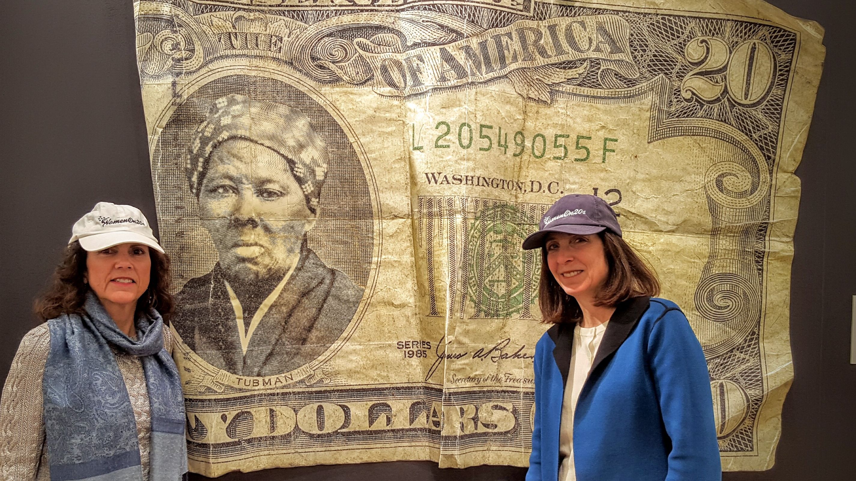 Barbara Ortiz Howard, left, and Susan Ades Stone, the women behind Women on 20s, an organization pushing for a woman on the $20 bill, stand before an artwork by Belgian artist Yann Guitton that was inspired by their  campaign. It was displayed recently at the Affordable Art Fair in New York City.