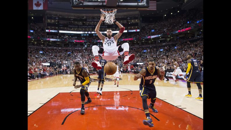 Toronto Raptors' Jonas Valanciunas, center, dunks the ball past Indiana Pacers' Lavoy Allen, left, and teammate George Hill during the second half in Game 1 in the first round of the  NBA basketball playoffs in Toronto on Saturday, April 16. 
