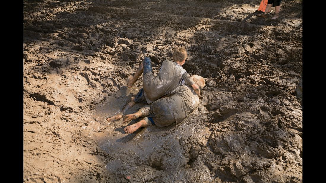 Children wrestle in the mud.