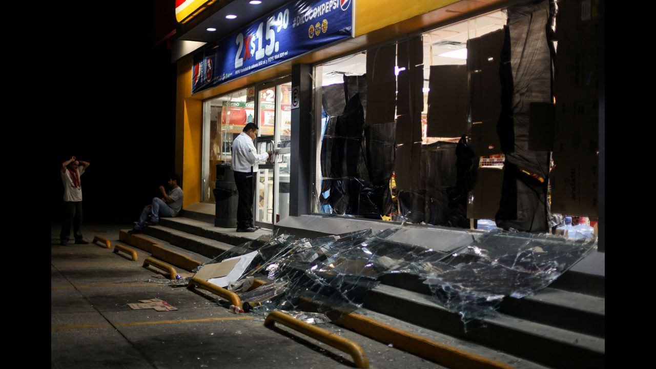 A security guard protects a store damaged by shock waves from the explosion.
