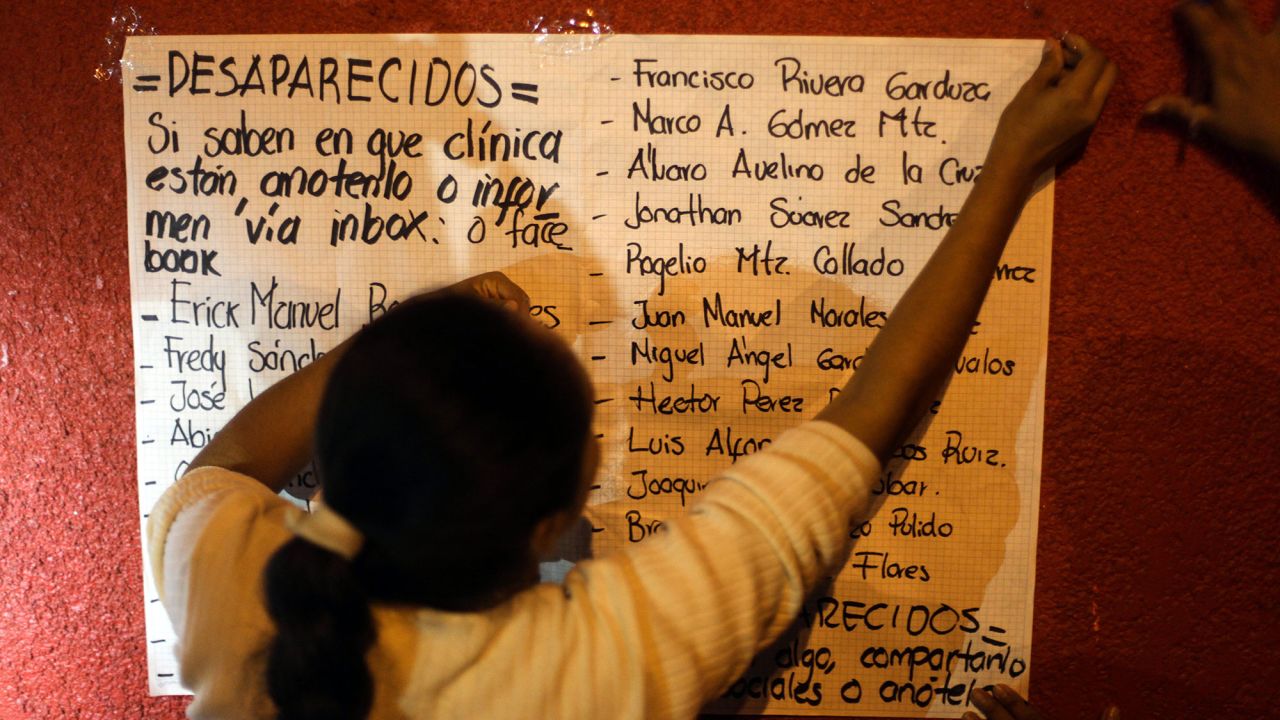A woman places a list of missing workers outside the hospital.