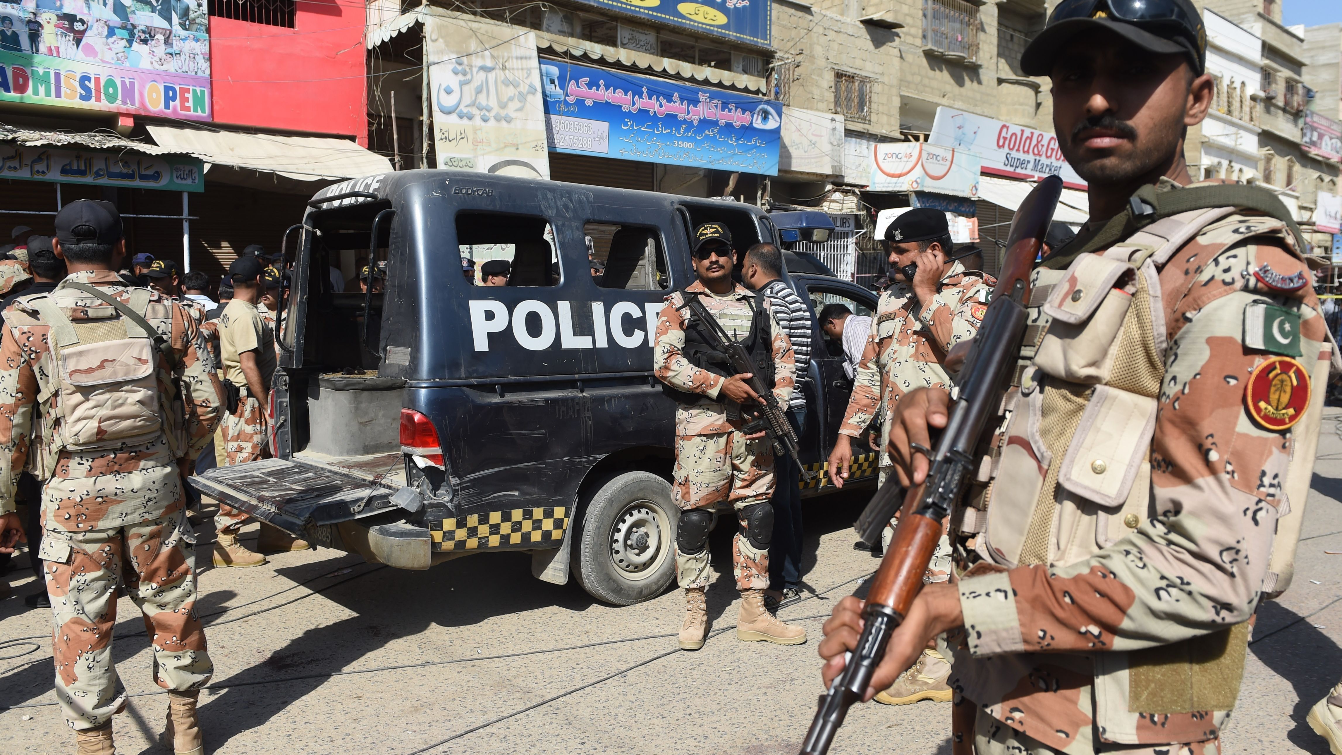 Pakistani security personnel gather around a police van after an attack by gunmen on security members guarding a polio vaccination team in Karachi on April 20, 2016.