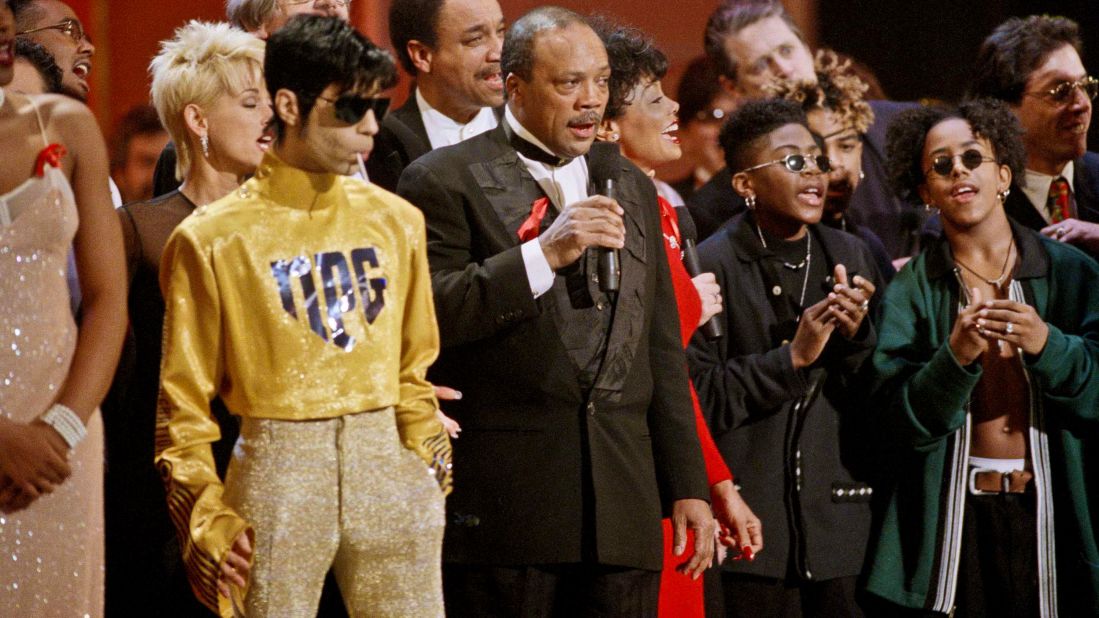 As dozens of singers perform "We Are The World" on the 10th anniversary of the African famine relief anthem, the artist formerly known as Prince stands sucking on a lollipop next to Quincy Jones at the American Music Awards in Los Angeles in 1995.