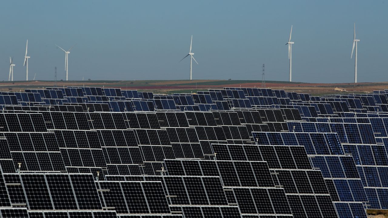 EL BONILLO, SPAIN - DECEMBER 02:  Photovoltaic power panels stand at Abaste's El Bonillo Solar Plant while wind turbines spin at a wind farm on the background on December 2, 2015 in El Bonillo, Albacete province, Spain. Spain in 2008 was a leading country on photovoltaic power and renewable energies but after some law changes the solar power industry collapsed, with companies either closing or turning to overseas markets. The UN Climate Change Summit is taking place in Paris over two weeks, in an attempt to agree on an international deal to curb greenhouse gas emissions.  (Photo by Pablo Blazquez Dominguez/Getty Images)