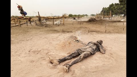 A Mundari man relaxes in the soft, peach-colored ash and dust of a dung fire. Zaidi says its consistency is close to that of talcum powder, and is applied to the skin as a means of sun protection.