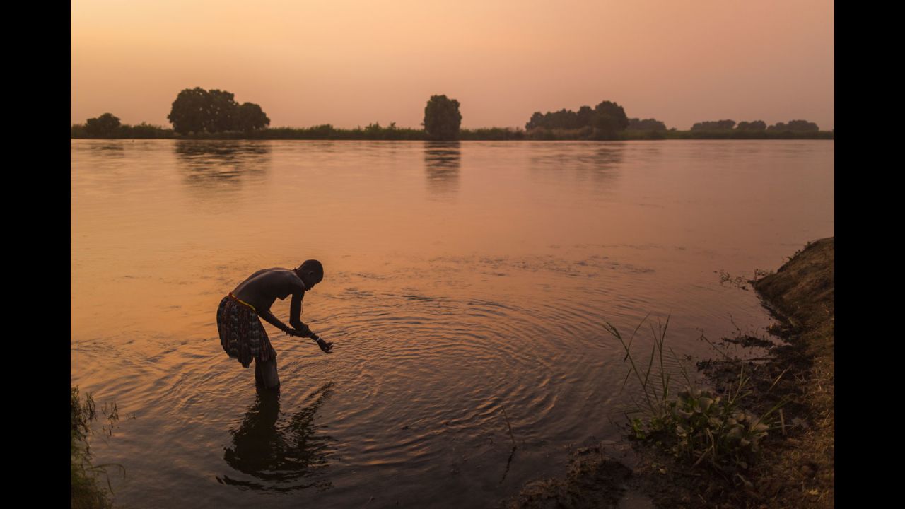 A Mundari tribeswoman washes herself in the Nile at sunset. Bathing in the river is a rare site according to the photographer.